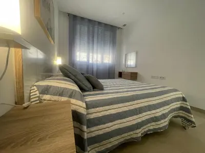 a bedroom with a large bed with a striped blanket at Dani Home in Cádiz