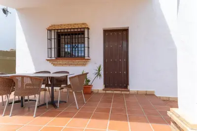 a patio with a table and chairs and a window at EntreCalas 4 Chalet con piscina privada en Conil, cala aceite, Roche viejo in Conil de la Frontera