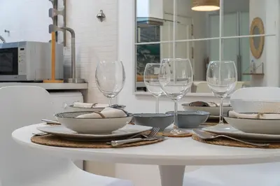 a white table with wine glasses and plates on it at Apartoyou - Polvorista Puerto in El Puerto de Santa María