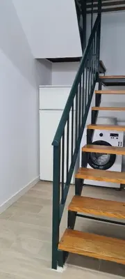 a staircase with wooden steps and a white wall at Dúplex Casa Ana Apartaclub La Barrosa in Chiclana de la Frontera