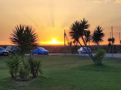 a sunset with cars parked in a field with palm trees at Dúplex Casa Ana Apartaclub La Barrosa in Chiclana de la Frontera