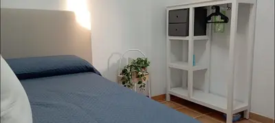 a bedroom with a bed and a white book shelf at Dúplex Casa Ana Apartaclub La Barrosa in Chiclana de la Frontera