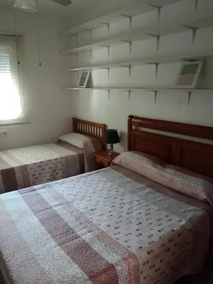 a bedroom with two beds and a window at Chalet Aquí No Es in Chiclana de la Frontera