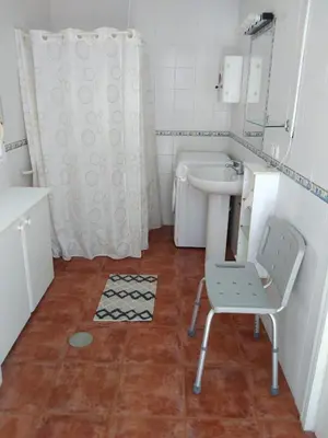a bathroom with a sink and a chair in it at Chalet Aquí No Es in Chiclana de la Frontera