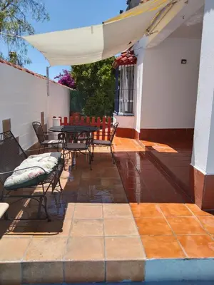 a patio with a table and chairs and an umbrella at Chalet Aquí No Es in Chiclana de la Frontera