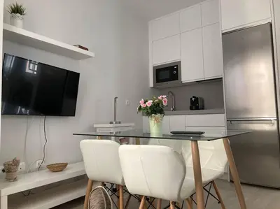 a kitchen with a table with chairs and a refrigerator at Apartamento Rota Progreso 5 in Rota