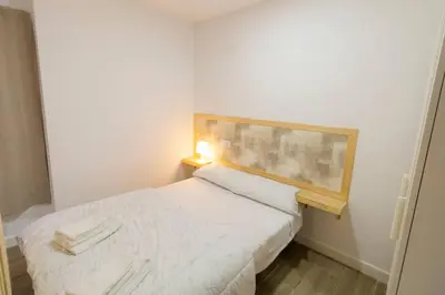 a small bedroom with a white bed with a wooden headboard at SH Loft del Mar. Cerca de la playa y el centro. AC in Cádiz