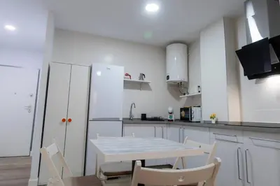 a white kitchen with a white table and chairs at SH Loft del Mar. Cerca de la playa y el centro. AC in Cádiz