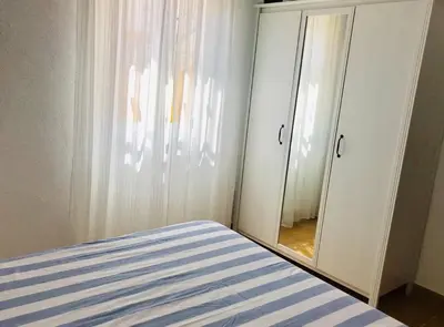 a bedroom with a bed and a dresser and a mirror at Apartamento con porche y piscina in Chiclana de la Frontera