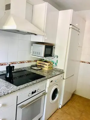 a kitchen with a white refrigerator and a washing machine at Apartamento con porche y piscina in Chiclana de la Frontera
