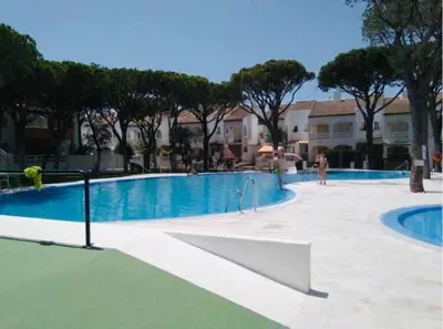 a swimming pool in a resort with people standing around it at Apartamento con porche y piscina in Chiclana de la Frontera