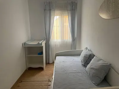 a small bedroom with a bed and a window at Apartamento con porche y piscina in Chiclana de la Frontera