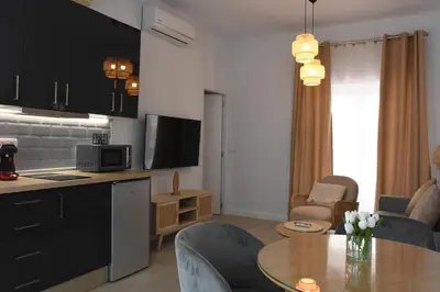 a kitchen and a living room with a table at CAPILLITA XXI APARTAMENTOS in Sanlúcar de Barrameda