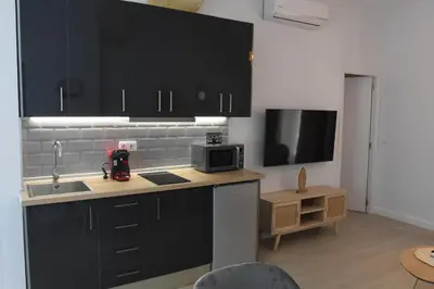 a kitchen with black cabinets and a sink and a microwave at CAPILLITA XXI APARTAMENTOS in Sanlúcar de Barrameda