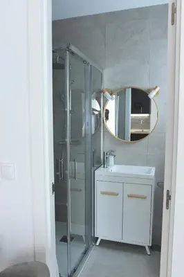 a bathroom with a shower and a sink and a mirror at CAPILLITA XXI APARTAMENTOS in Sanlúcar de Barrameda