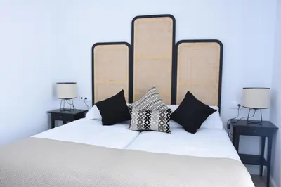 a bed with black and white pillows on it at CAPILLITA XXI APARTAMENTOS in Sanlúcar de Barrameda