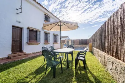 a table and chairs with an umbrella on a yard at EntreCalas 3 chalet piscina privada Conil, Roche Viejo, Cala del Aceite in Conil de la Frontera