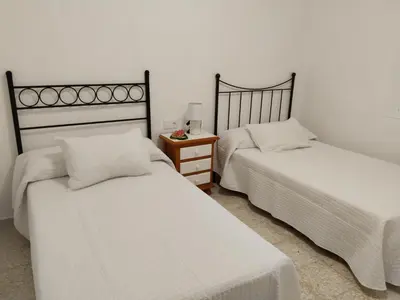 a bedroom with two beds and a table with a lamp at Casa EDU in Sanlúcar de Barrameda