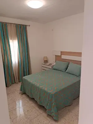 a bedroom with a bed with a green bedspread at Casa EDU in Sanlúcar de Barrameda