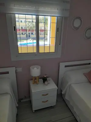 a small bedroom with two beds and a window at Apartamento Marisma del Guadalquivir in Sanlúcar de Barrameda
