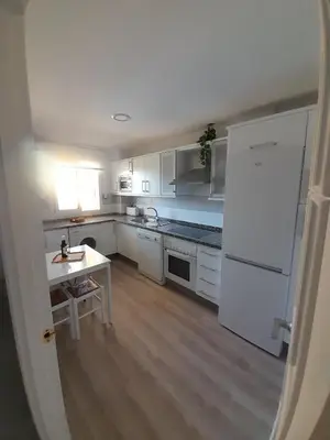 a kitchen with a white refrigerator and a table at Apartamento Marisma del Guadalquivir in Sanlúcar de Barrameda