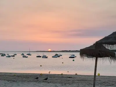 a group of boats in the water at sunset at Apartamento Marisma del Guadalquivir in Sanlúcar de Barrameda