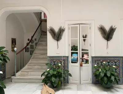 a hallway with a door and stairs with plants at CASA PALACIO LAS MARÍAS - Casa en exclusividad in Cádiz