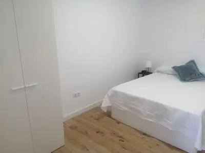 a bedroom with a white bed and a wooden floor at Apartamento/Flat San Fernando Cádiz in San Fernando