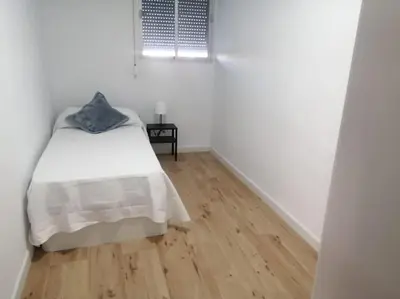 a white bedroom with a bed and a wooden floor at Apartamento/Flat San Fernando Cádiz in San Fernando