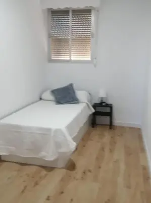 a white bedroom with a bed and a wooden floor at Apartamento/Flat San Fernando Cádiz in San Fernando