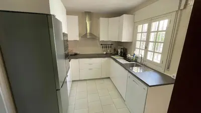 a kitchen with white cabinets and a black refrigerator at Quinta La Solana in Chiclana de la Frontera
