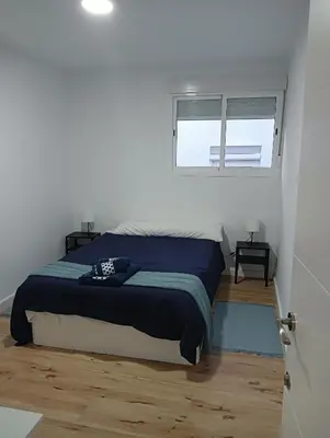 a bedroom with a bed with a blue blanket and a window at 3 bedroom Apartment in San Fernando in San Fernando