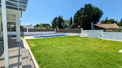 a backyard with a pool and a grass yard at Conil fuente del gallo in Conil de la Frontera
