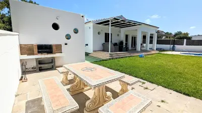 a backyard of a white house with a table at Conil fuente del gallo in Conil de la Frontera