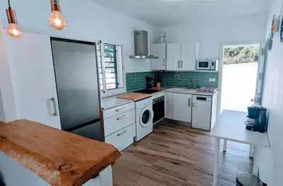 a kitchen with white appliances and a wooden floor at Conil fuente del gallo in Conil de la Frontera