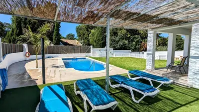 a swimming pool with two lounge chairs and a swimming pool at Conil fuente del gallo in Conil de la Frontera