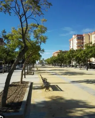 a park bench next to a tree on a sidewalk at Apartamento Plaza Calzada 2 in Sanlúcar de Barrameda