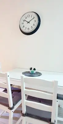 a clock on a wall above a table and a chair at Apartamento Plaza Calzada 2 in Sanlúcar de Barrameda