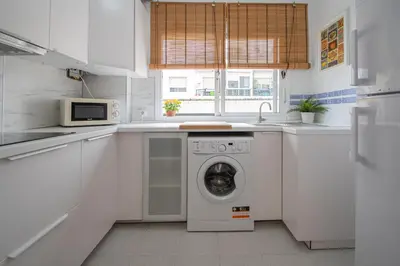 a white kitchen with a washing machine in it at El Rosal de Huertas in Cádiz