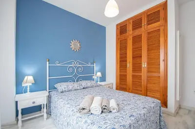 a bedroom with a bed with two pairs of slippers on it at El Rosal de Huertas in Cádiz