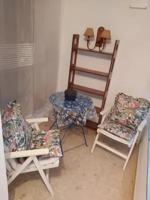 a room with two chairs and a table and a shelf at Avenida Portugal con Ascensor Grupo AC Gestión in Cádiz