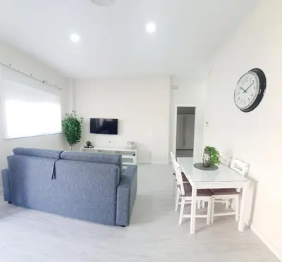 a living room with a couch and a table and a clock at Apartamento Plaza Calzada 3 in Sanlúcar de Barrameda