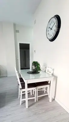 a dining room with a table and a clock on the wall at Apartamento Plaza Calzada 3 in Sanlúcar de Barrameda