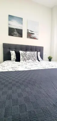 a bedroom with a large bed with two pictures on the wall at Apartamento Plaza Calzada 3 in Sanlúcar de Barrameda