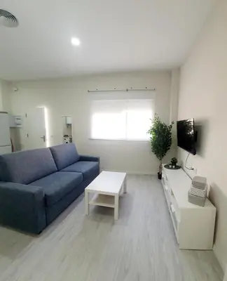 a living room with a blue couch and a table at Apartamento Plaza Calzada 3 in Sanlúcar de Barrameda