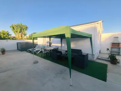 a green tent on a patio with chairs and tables at Casa en Chiclana de la Frontera, Playa La Barrosa in Chiclana de la Frontera