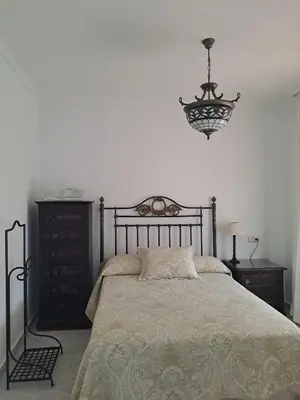 a bedroom with a bed and a chandelier at Al sur del sur in Sanlúcar de Barrameda