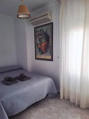 a bedroom with a bed and a painting on the wall at Al sur del sur in Sanlúcar de Barrameda