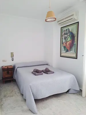 a bedroom with a bed and a painting on the wall at Al sur del sur in Sanlúcar de Barrameda