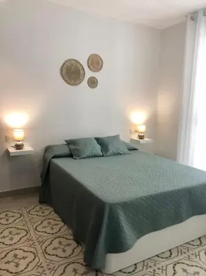 a bedroom with a green bed with two lights on the wall at Apartamento en Plaza Plateros in Jerez de la Frontera